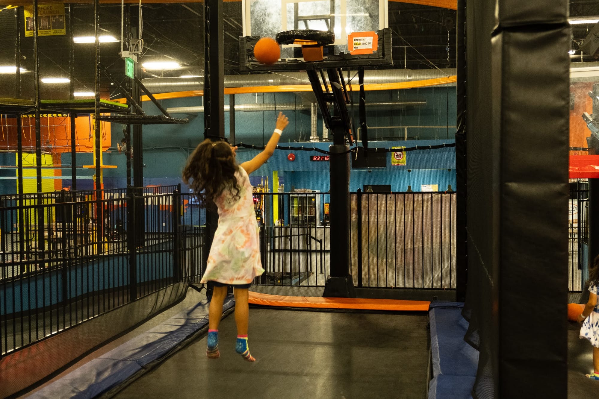 Girl throwing a basketball at Urban Air Waco indoor trampoline basketball court