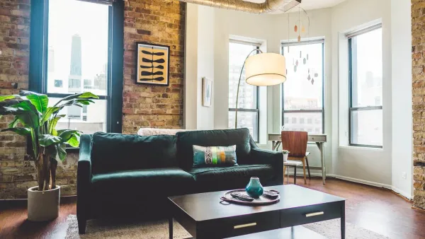 Living room inside a small apartment with wood floors and brick accent wall and staged as an occupied rental