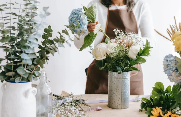 faceless woman arranging flowers in vase