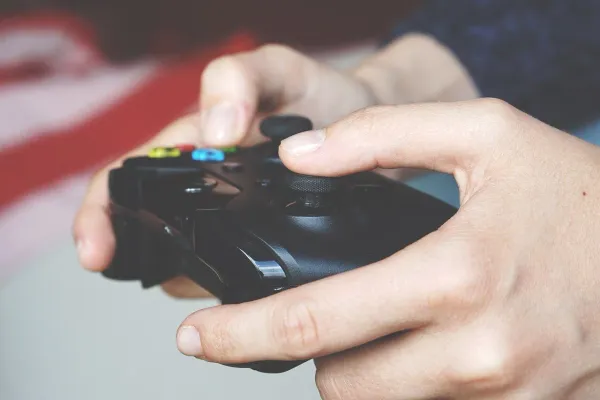 Gamer holding xbox controller while playing video game online