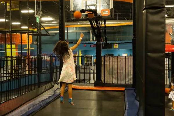 girl tossing a basketball into the hoop at Urban Air, an indoor playground in Waco, Tx.