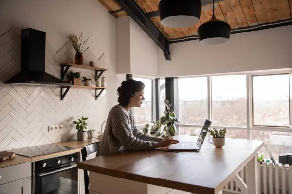 young woman surfing internet on laptop in kitchen