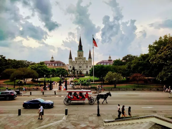 New Orleans French Quarter from across the street from the cathedral with a horse-drawn carriage riding down the road